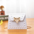White jelly mini crossbody bag with square studs and golden chain strap on wooden surface - White