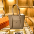 Grande borsa tote grigio elefante con tasca argentata esposta su uno scaffale boutique - Cachi