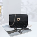 Black quilted leather chain bag with a gold heart lock on a stylish white surface - Black
