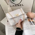 Witte gewatteerde crossbodytas met gouden ketting en draaisluiting in de hand - Wit