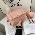 Pink quilted crossbody bag with gold chain strap and turn-lock closure on white table - Pink