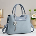 Detailansicht der graublauen Lederhandtasche mit Flechtmuster und Blumenanhänger - Hellblau