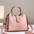 Pink crocodile pattern handbag with gold hardware and adjustable strap on neutral background - Pink