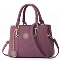 Detail of deep purple faux leather handbag with braided V-shape pattern and gold hardware - Dark Purple