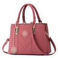 Detail of rose red leather tote bag showing V-shaped stitching and golden hardware charm - Dusty Pink