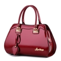 Glossy burgundy patent leather handbag with gold hardware and leaf pendant charm - Burgundy