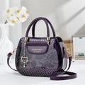 Purple snakeskin tote bag with gold handles and cat charm shown in a lifestyle setting - Purple