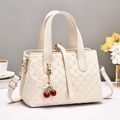 Gesteppte cremefarbene Handtasche mit Strassdetails und Kirsch-Anhänger in Lifestyle-Szene - Gebrochenes Weiß