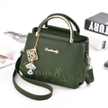 Forest green leather handbag with rose embroidery and gold handle in lifestyle setting - Dark Green