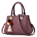 Elegant purple leather handbag with pompom tassel from a professional 45-degree angle - Purple