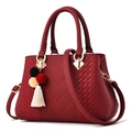 Elegant deep red leather handbag for women featuring V-shaped stitching and tassel charm - Burgundy