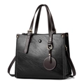 Classic black tote bag with brown handles and gold hardware on white background - Black
