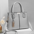 Grey pebbled leather tote bag with gold hardware on white pedestal display - Light Gray