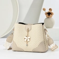 Beige woven bucket bag with leather accents and a delicate white bow pendant - Khaki