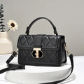 Quilted black leather handbag with gold T-clasp and top handle on a white pedestal - Black