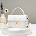 White quilted crossbody bag with gold metallic clasp on a minimalist display stand - White