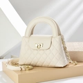Gesteppte cremefarbene Lederhandtasche mit goldenem Schloss und Kettenriemen auf Hintergrund - Weiß