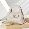 Schicke beige Stepptasche mit Goldschloss und Kettenriemen auf geometrischem Sockel - Grau
