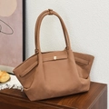 Large warm brown faux suede tote bag with golden buckle on a wooden cabinet - Brown
