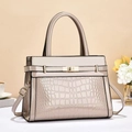 Detail of beige crocodile pattern handbag with elegant metal twist lock and top handle - Khaki