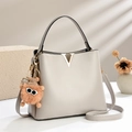 Fashionable beige bucket bag with gold V-hardware and cute plush charm detail - Gray