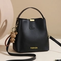 Classic black bucket bag in matte PU leather featuring a golden bear charm and strap - Black
