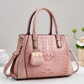 Detalle de bolso rosa con grabado de cocodrilo, mini colgante y herrajes dorados - Rosa