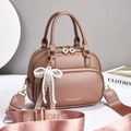 Detail of brown leather handbag featuring a pearl bow lace pendant and wide strap - Dusty Pink