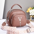 Detail of dust pink handbag showing triple-zipper design and geometric woven strap - Dusty Pink