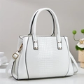 White crocodile embossed tote bag with dual handles and gold hardware in a sleek studio view - White