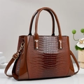 Detail of dark brown tote bag with glossy crocodile texture and gold hardware - Coffee
