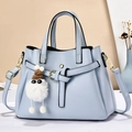 Light blue faux leather handbag with bow charm and detachable strap on neutral background - Blue