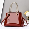 Glossy burgundy patent leather handbag with gold hardware and woven handle - Red