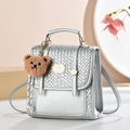 Mini zaino metallizzato argento con patta intrecciata e ciondolo orsetto marrone - Stile Intrecciato / Argento