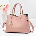 Elegant pink women's handbag with gold hardware and heart pearl charm in studio setting - Pink