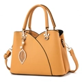 Mustard yellow pebble leather handbag with gold hardware and leaf pendant charm - Yellow