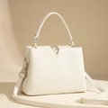 Detailed close-up of ivory pebble leather handbag with gold V-shaped metal buckle accent - Beige
