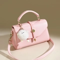 Vue détaillée du sac en cuir rose montrant le grain de litchi et le pompon blanc - Rose