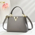 Gray lychee leather handbag with gold V logo and shoulder strap on a white surface - Gray