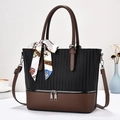 Two-tone tote bag with black pleated texture and brown leather straps in a home setting - Black