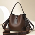Deep brown bucket bag with wide textile strap and leather handle on minimalist background - Coffee