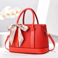 Elegant red pebbled leather bucket handbag with decorative silk scarf and gold hardware - Red