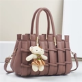 Detail of woven texture on purple leather handbag with a teddy bear charm and metal hardware - 28*14*18CM / Mauve