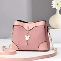 Pink pleated bucket bag with gold chain strap and bunny pendant in a minimalist setting - Pink