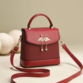 Sac à main rouge avec boucle cygne dorée et pompons perles sur fond minimaliste - Bordeaux