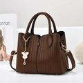Bolso de mano de cuero marrón oscuro con adorno de oso dorado y correa extraíble - café