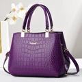 Bolso de mano morado con grabado de cocodrilo, logo KUOY, asa superior y correa ajustable - Púrpura