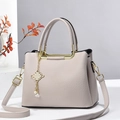 Bolso de mano beige en piel de grano lichi con detalles dorados y borla elegante - Gris claro