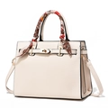 Elegante cremeweiße Trapez-Handtasche mit Goldschloss und Seidenschal am Griff - Cremeweiß