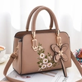 Light brown soft leather tote with floral embroidery and butterfly pendant in lifestyle setting - Khaki